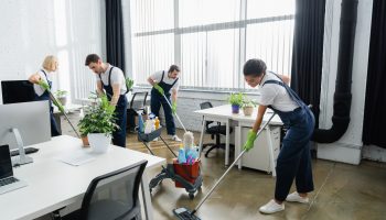 Multiethnic cleaners washing floor together in office Multiethnic cleaners washing floor together in office