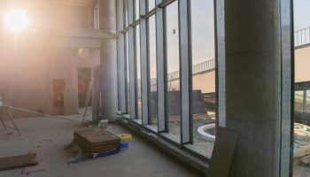 251755039_m A captivating view of a modern business building under construction, showcasing its raw industrial interior with exposed steel beams and concrete walls bathed in the warm, golden hues of a sunset